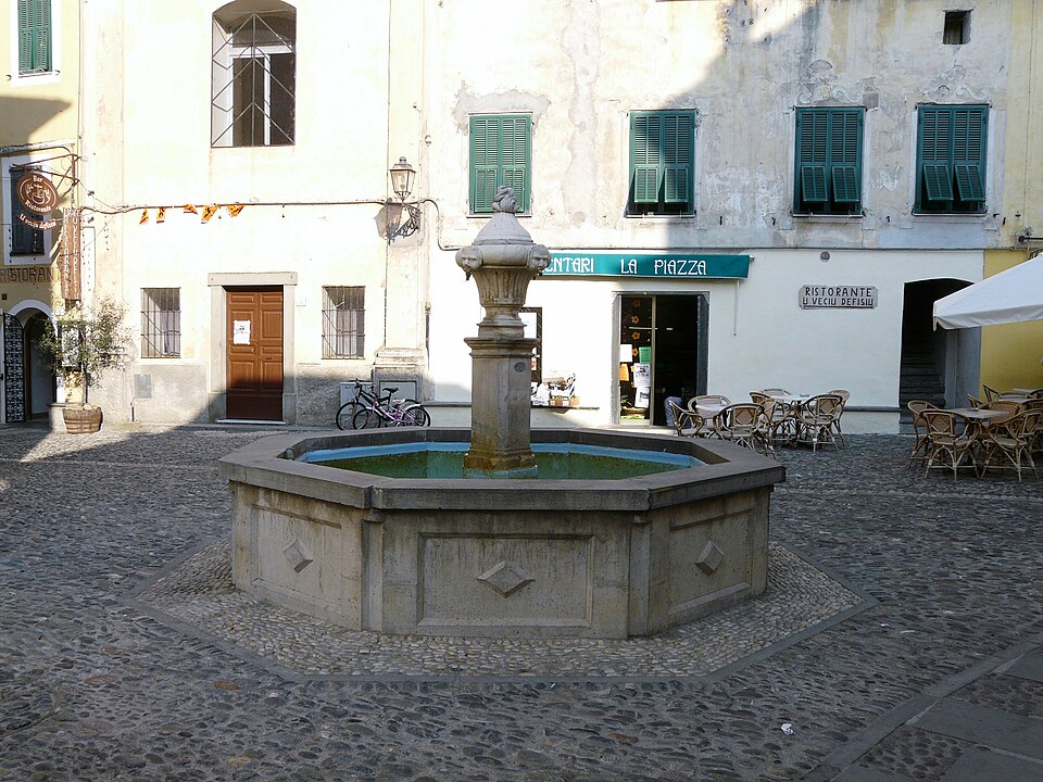 The stone fountain in the central piazza of Airole, surrounded by traditional Ligurian buildings