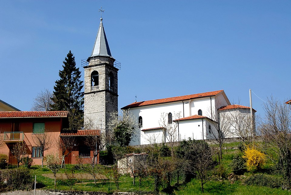 Mountain village of Porzûs showing the Church of Saints John the Baptist and Lucia amid green hills in the municipality of Attimis