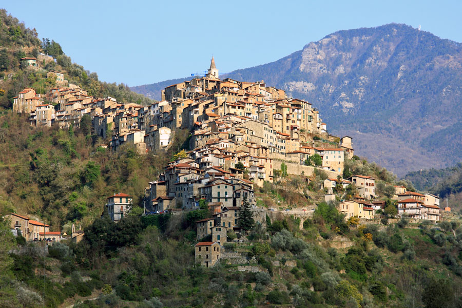 Panoramic view of Apricale showing concentric stone houses rising on a sunlit hillside in the Province of Imperia, Liguria